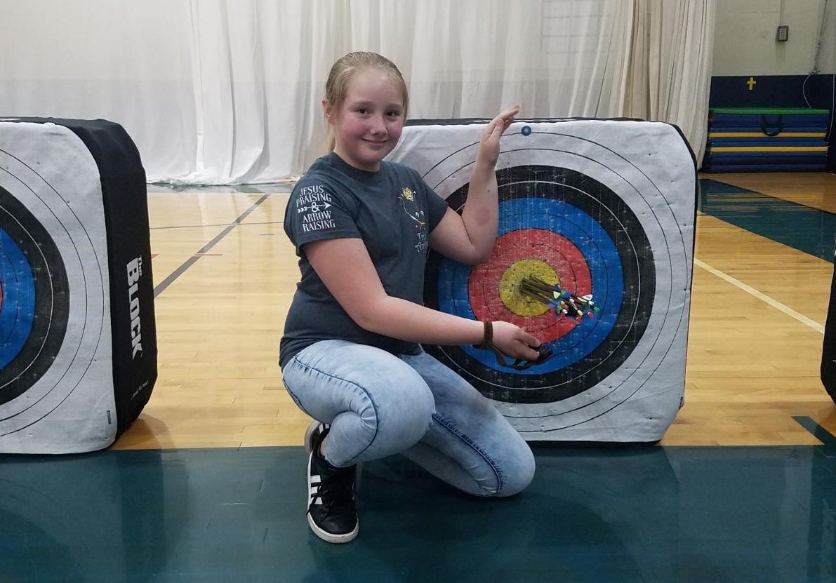 Sydney King poses next to a archery target.