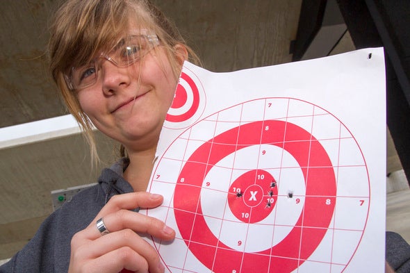 16 year old student holding up her target from shooting a .22 rifle.