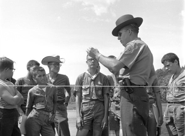 A conservation agent speaks with a group of boy scouts in the 1950s.