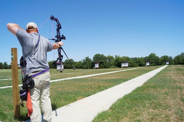 male archer shooting compound bow at target