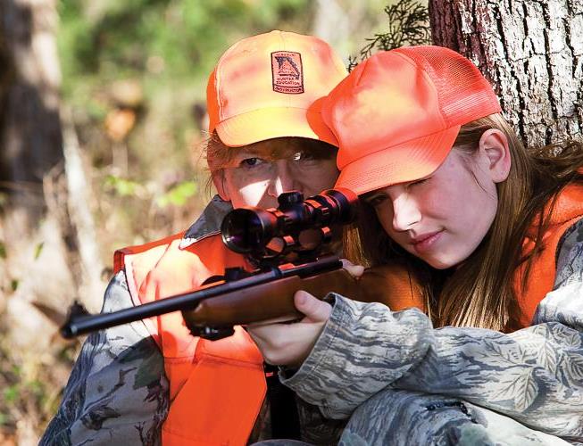 Young deer hunter being mentored by adult