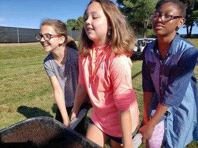 kids delivering mulch in wheel barrow