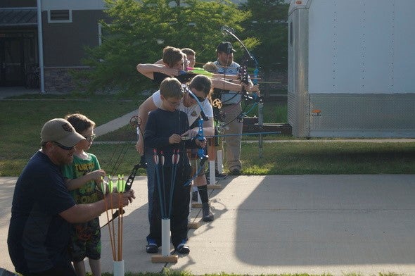 A family shoots arrows from crossbows during an MDC archery clinic.