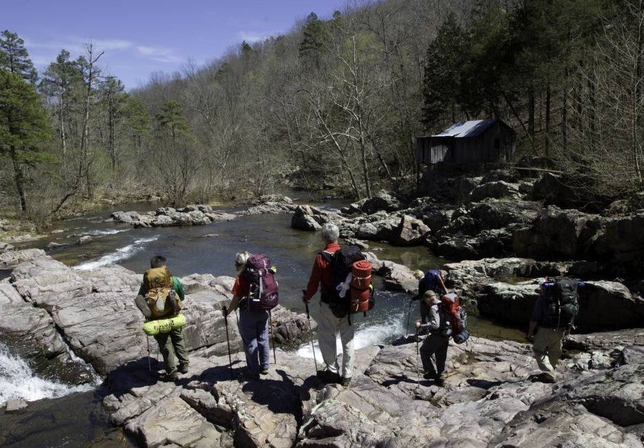 A family backpacks near a river