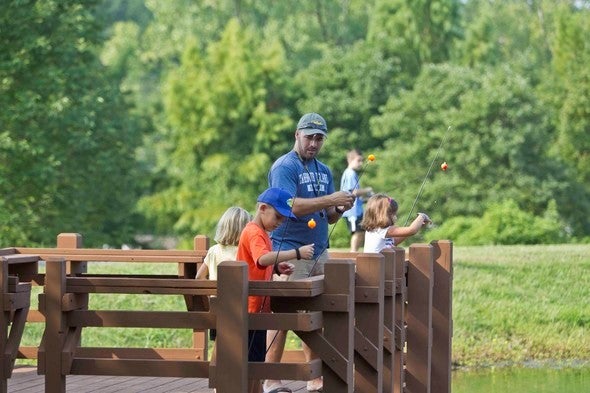 A father and son learn how to fish at a Missouri pond.