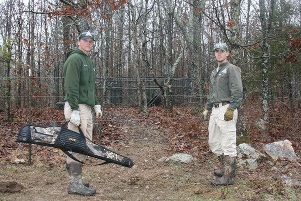 two feral hog trappers standing in front of trap