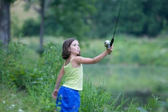 young girl casts a fishing rod and reel for trout fishing