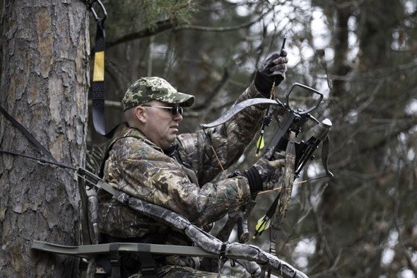 A hunter loads his crossbow in the woods.