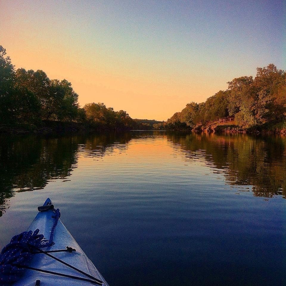 A kayak floats on the Gasconade River at sunset.