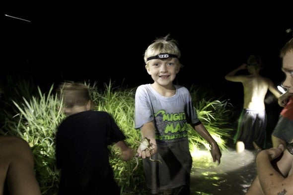 A young boy holds a frog during a gigging trip at a Missouri pond.