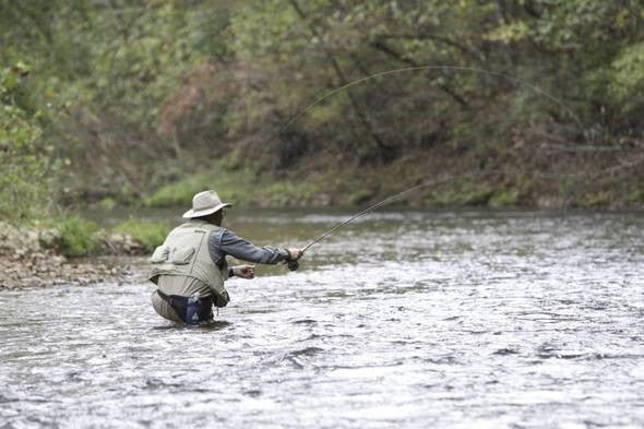 man trout fishing in stream