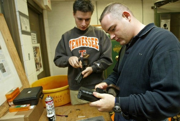 Two men clean handguns.