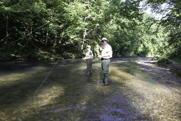 two people fly fishing in stream