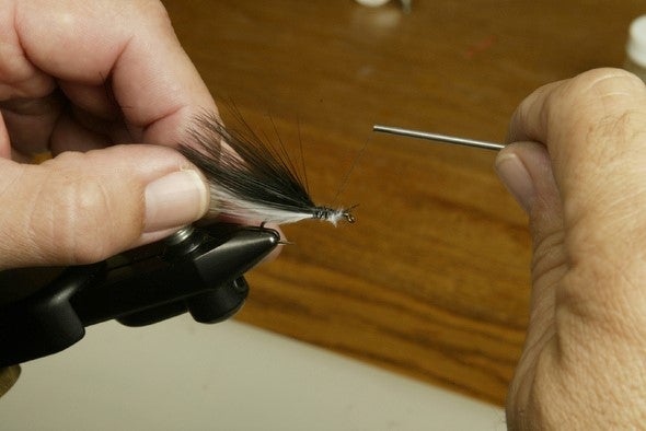 closeup of a person's hand tying a fishing fly