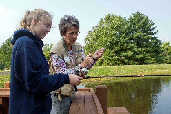 woman teaching fishing to girl