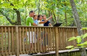 A family stands on a walkway at a nature center.