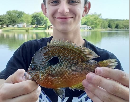 A smiling thirteen year old Robert Audrain IV holds his longear sunfish.