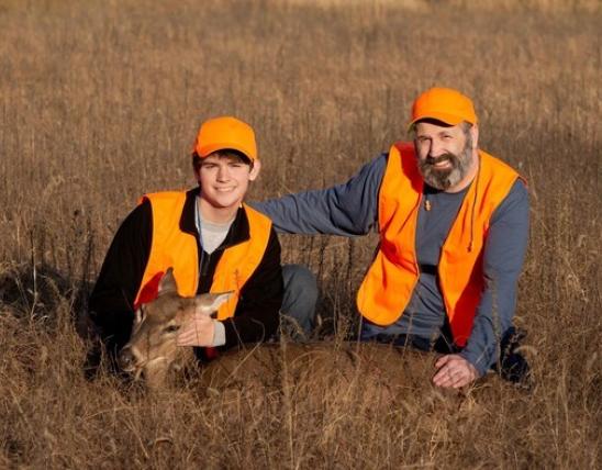 Youth hunter with harvested deer and mentor