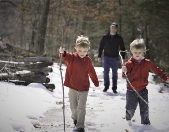 Dad and two young sons taking a hike in the snow