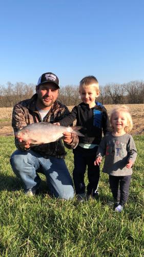 Brian Rehmeier holds his state record gizzard shad. His children, Jack and Emma, are standing beside him