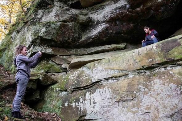 A mom takes a picture of her son in a rock formation at Poosey Conservation Area.