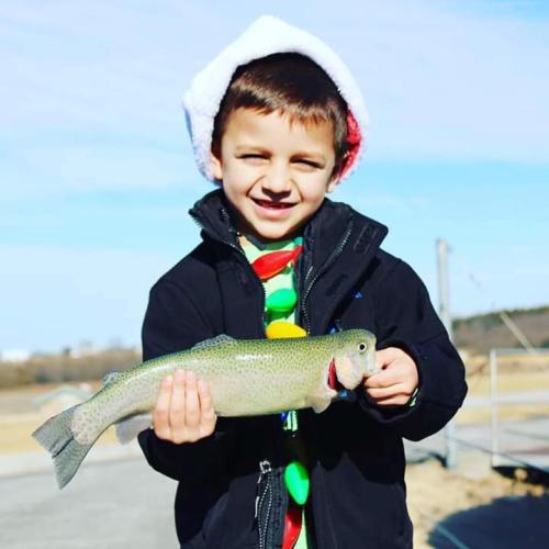 Boy in Santa Hat holds rainbow trout