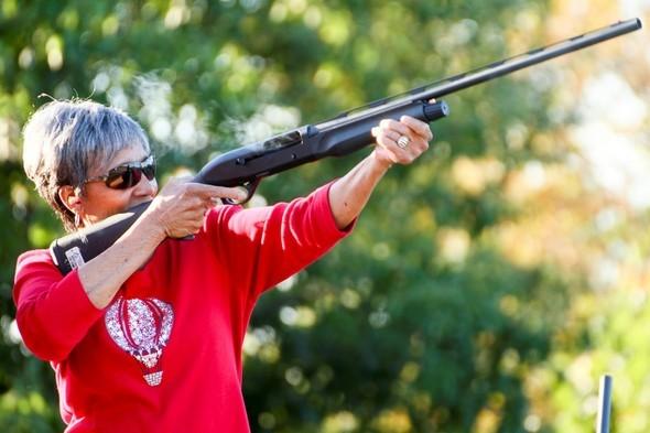 Woman shoots shotgun at outdoor shooting range