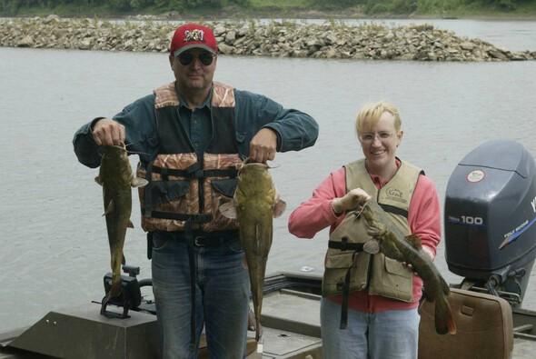 Man and woman hold catfish caught using a trotline