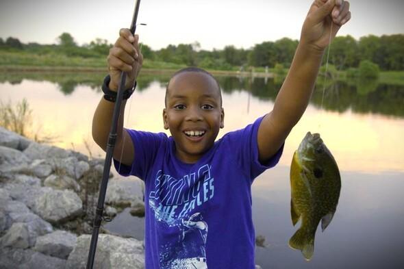 Boy smiles with a bluegill fish