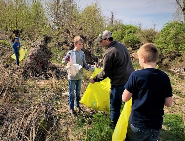 Man and boys clean up trash in natural area