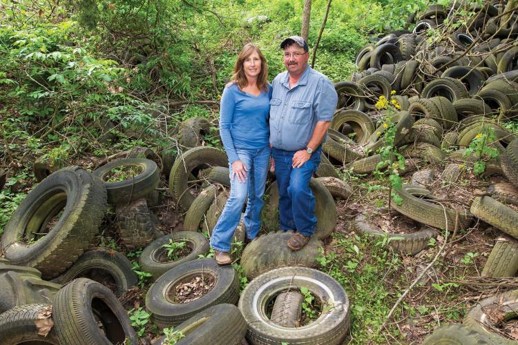 Laura and Kevin Hayden standing in a ravine covered in old tires