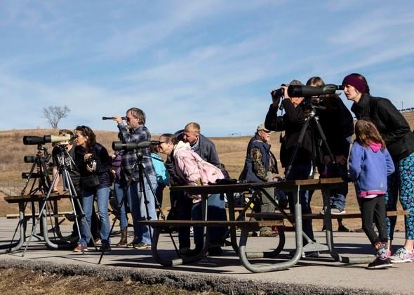 Spectators use cameras and other equipment to watch for bald eagles.