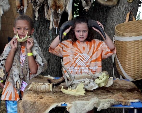 two kids play with animal skull and horns