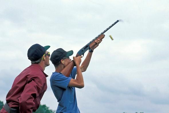 An MDC staff member teaches a teenager how to shoot a shotgun.