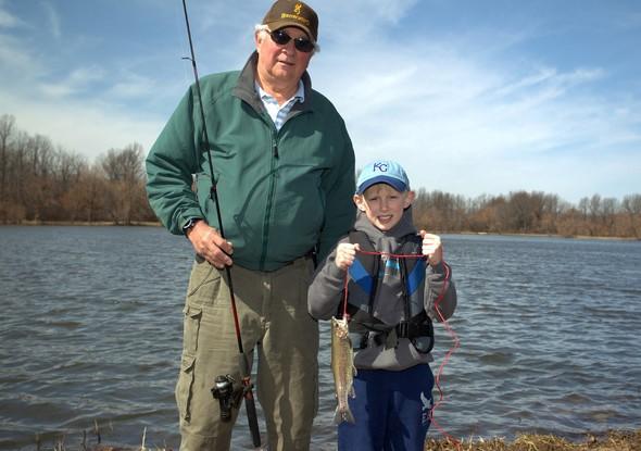 A grandfather and his grandson show off a trout they caught.