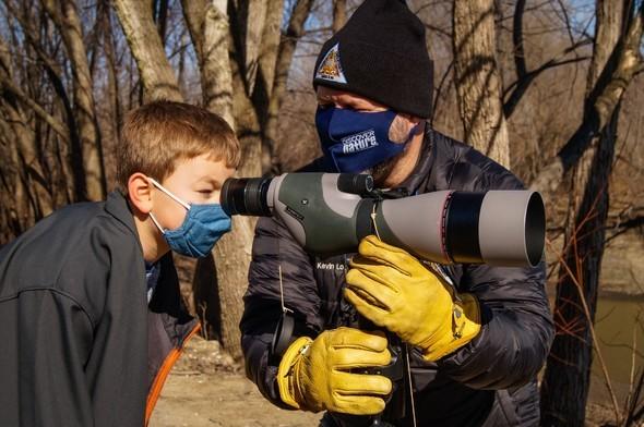 A young boy looks for bald eagles with MDC staff during an Eagle Days event.