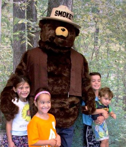 Children posing with Smokey the Bear