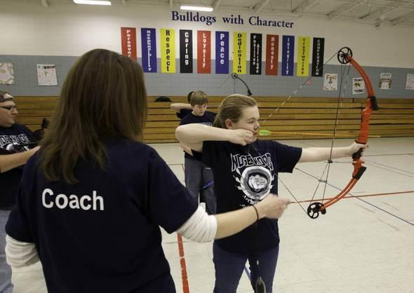 Teacher helping kids with archery.