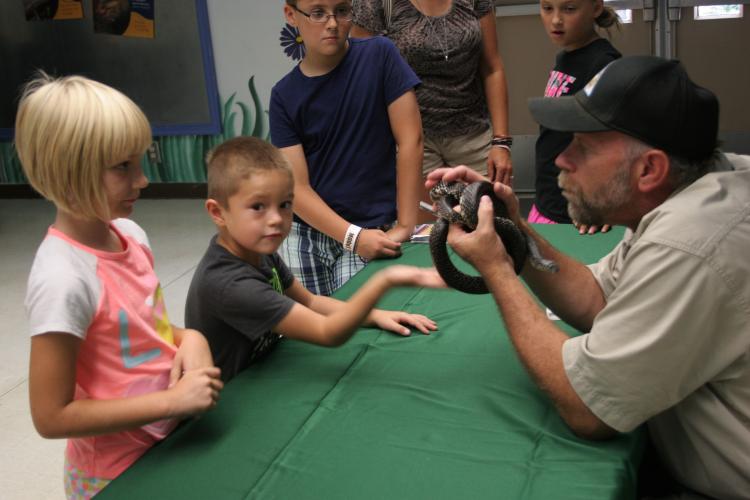 MDC staff person shows kids a king snake at the state fair