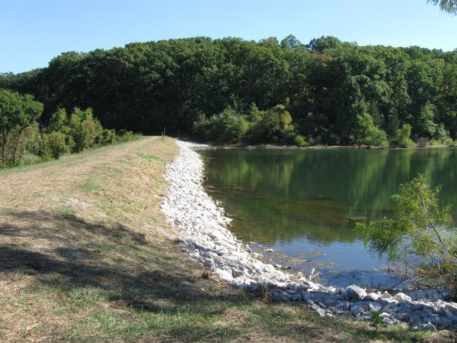 View of lake dam with rock waterline.