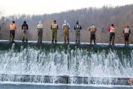 Several anglers stand along a bank on opening day of trout season