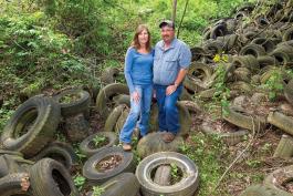 Laura and Kevin Hayden standing in a ravine covered in old tires