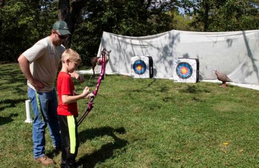 man teaching boy archery
