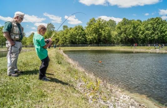 Boy reels in fish from lake.