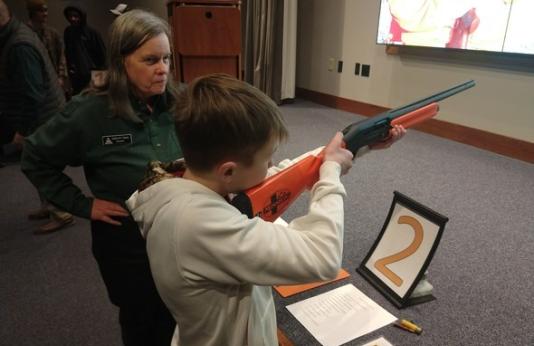 woman teaching firearm safety to boy