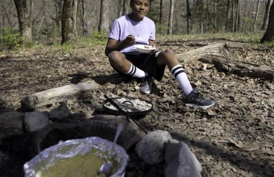 Boy enjoys dutch oven meal in nature