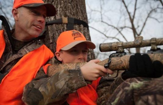 Father daughter deer hunting with rifle in woods