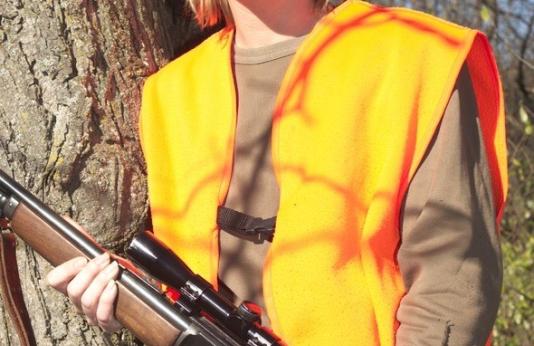 Woman deer hunter in woods with rifle