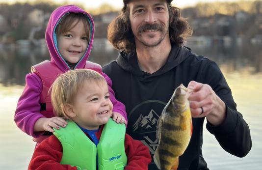 Jeffrey Needles holds a state record yellow perch with his young daughter and son