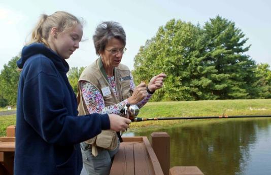 Volunteer helps girl to fish